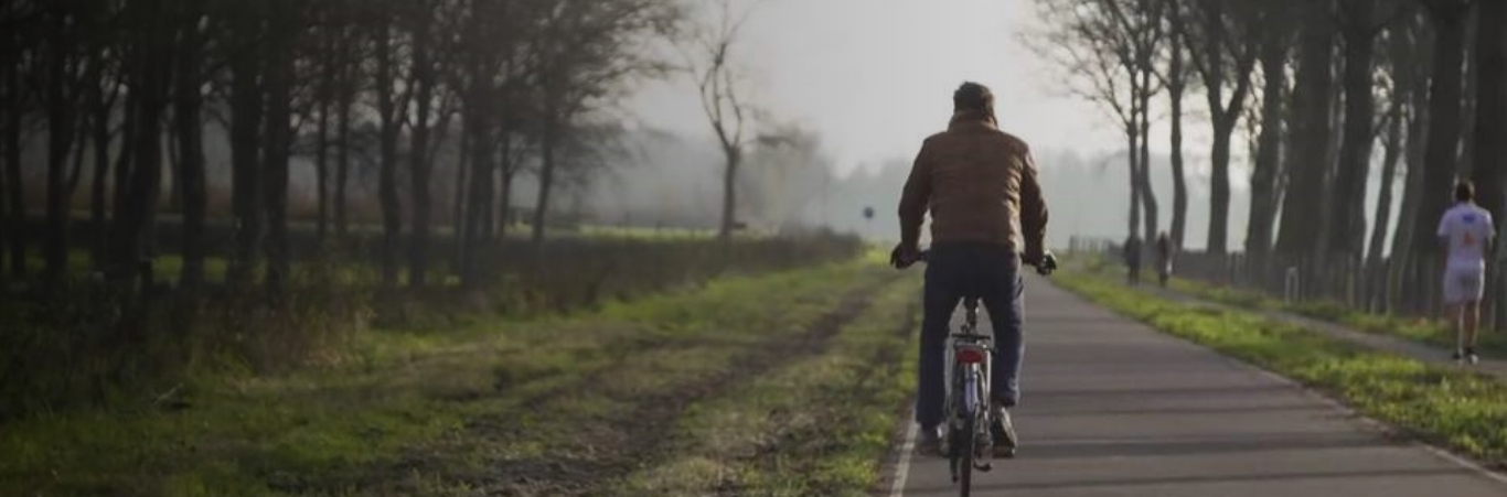 Een man fietst op een pad in het bos.