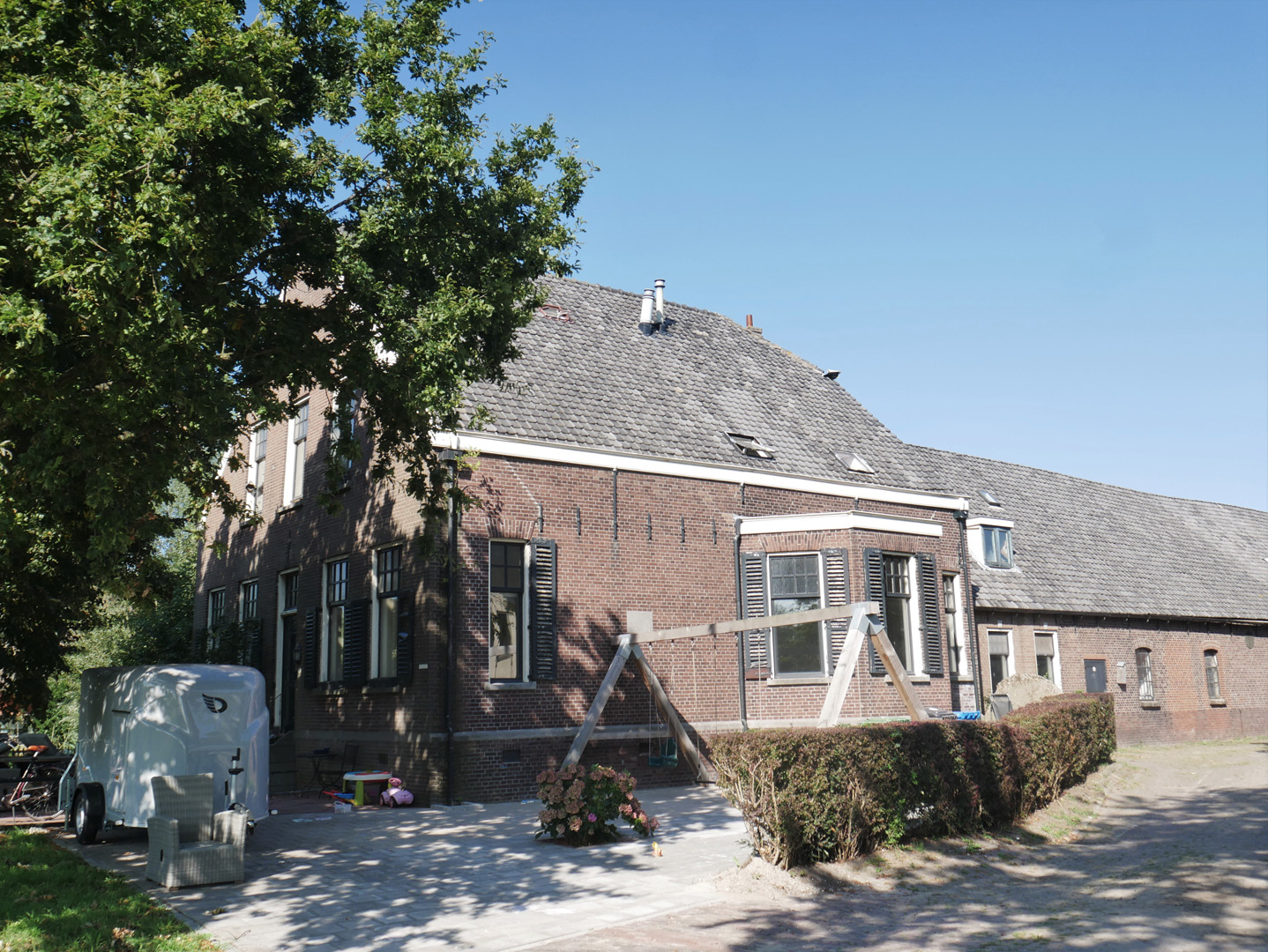 Een vrijstaand huis met een een schommel in de tuin.