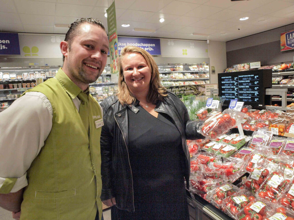 Een supermarktmedewerker en een klant bij de tomaten