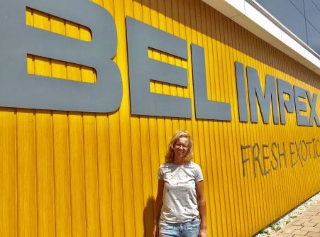 Een vrouw die voor een gele muur staat met de letters belimpex