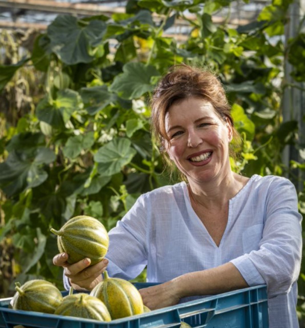 Een vrouw die in een kas staat en poepoenen vast heeft